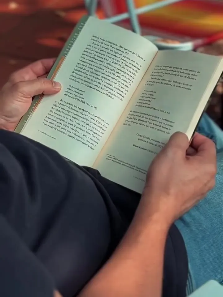 Pessoa lendo um livro sentada numa cadeira de praia colorida.