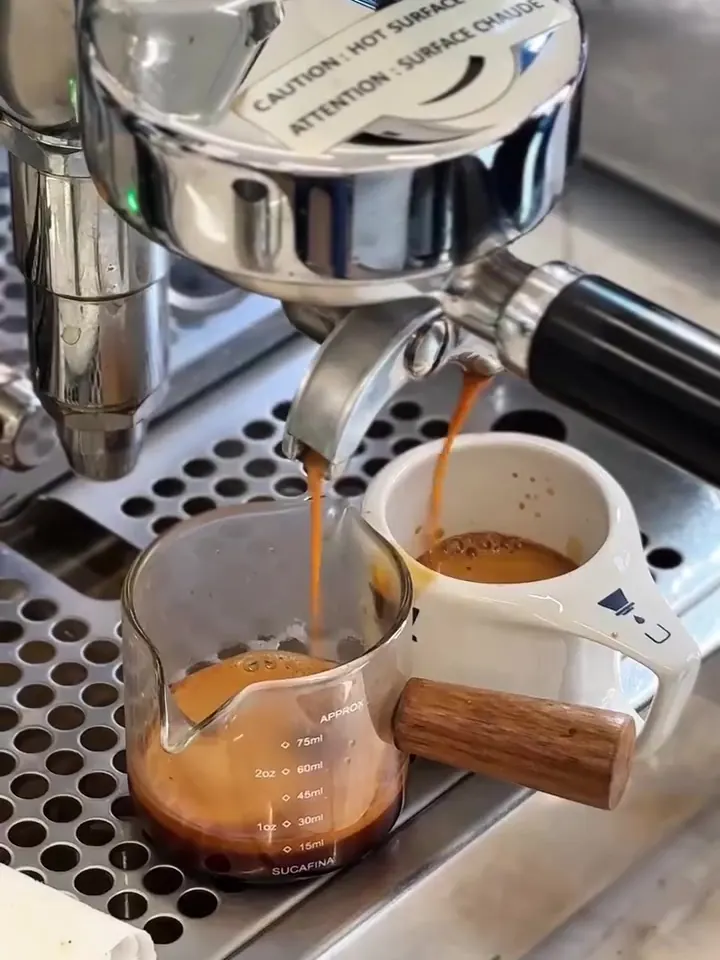 Espresso sendo extraído na máquina, direto para a jarrinha e a xícara.